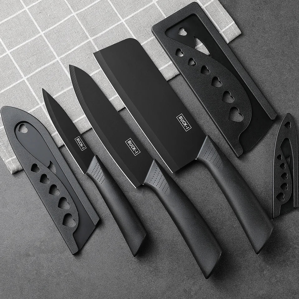 A set of black kitchen knives with matching black protective sheaths, arranged diagonally on a dark gray textured surface with a white grid-patterned cloth in the background.